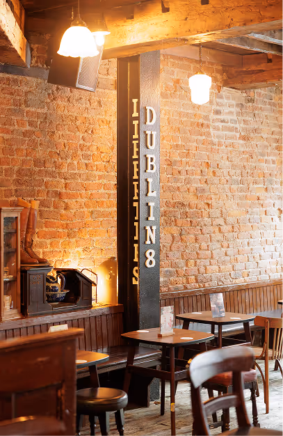 Dublin 8 lettering on an iron column beside exposed brick and timber tables at John's Bar & Haberdashery