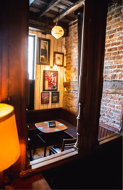 Private snug with a table for two and framed prints at John's Bar & Haberdashery