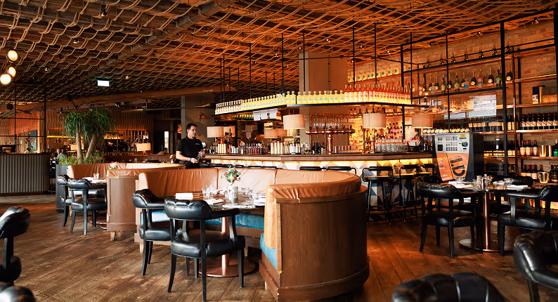 Curved leather booths and a lit central bar under a woven ceiling at Mackenzie's