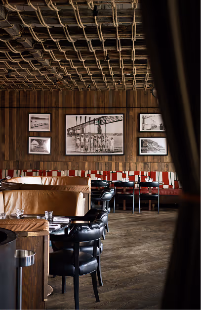 Black leather tub chairs and red striped banquettes below framed archive photographs at Mackenzie's