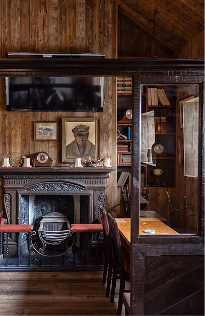 Carved cast-iron fireplace and framed portrait in the timber-panelled bar at Foxhunter