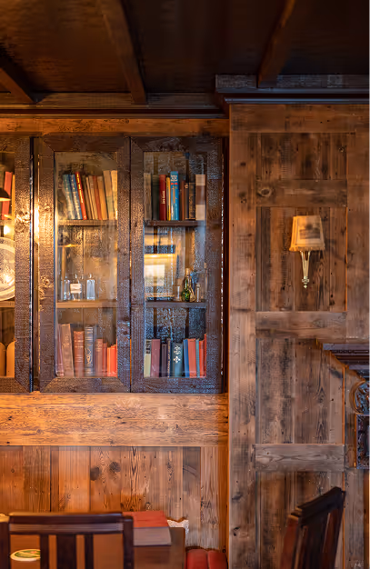 Glazed bookcase of vintage books set into reclaimed timber panelling at Foxhunter