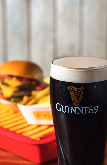 Pint of Guinness with a cheeseburger and fries in a red basket at Wowburger
