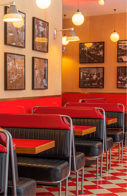 Row of red and black booths and globe pendant lights in the diner at Wowburger