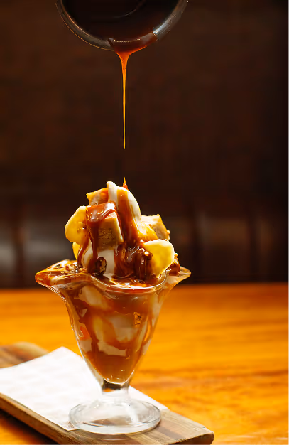 Caramel sauce poured over a banana and ice cream sundae at Fade St. Social
