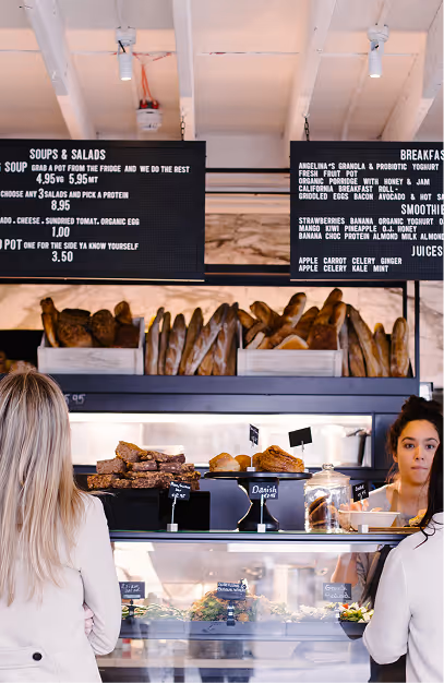 Bread and pastry counter under handwritten menu boards at Angelina's Deli