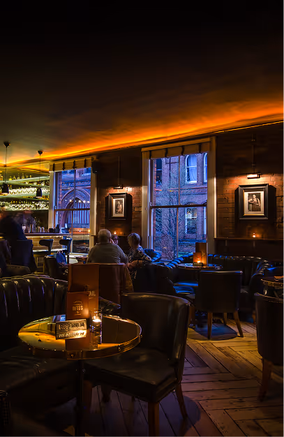 Guests at brass-topped tables and leather chairs in the brick-walled bar at Fade St. Social