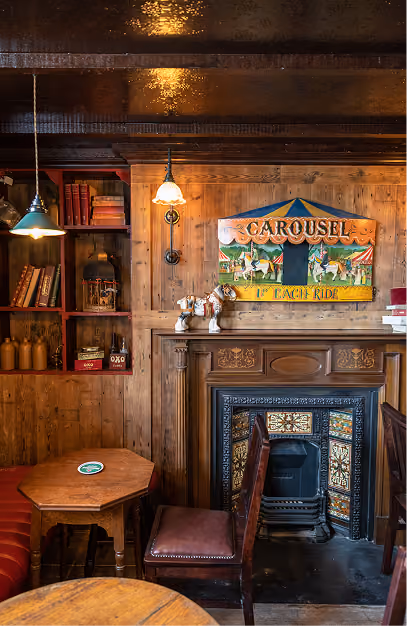 Tiled cast-iron fireplace and vintage carousel sign in a timber-panelled snug at the Foxhunter