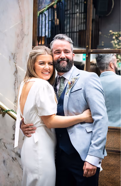 Bride and groom embracing beside a marble wall at The Grayson