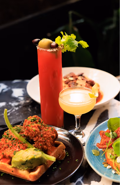 Bloody Mary, coupe cocktail and a savoury waffle with avocado on a marble table at Isabelle's