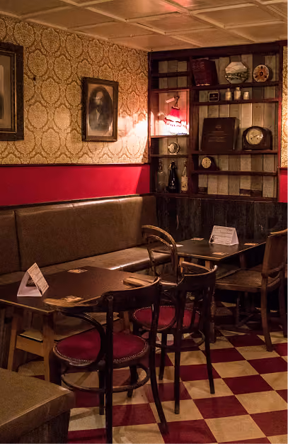 Bentwood chairs and a leather bench on a red chequerboard floor at Mary's Bar & Hardware