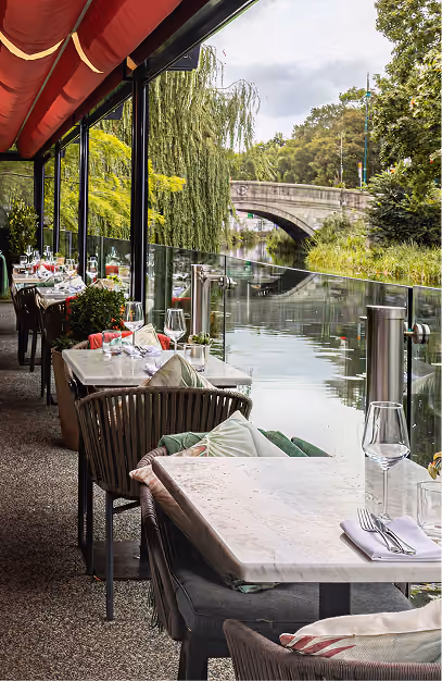 Marble tables under a red awning on the canalside terrace at Angelina's