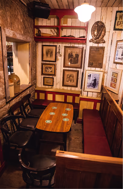 John's Bar with vintage framed artwork, wooden tables, dark seating and warm ambient lighting.