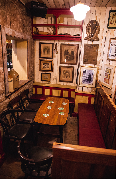 John's Bar with vintage framed artwork, wooden tables, dark seating and warm ambient lighting.