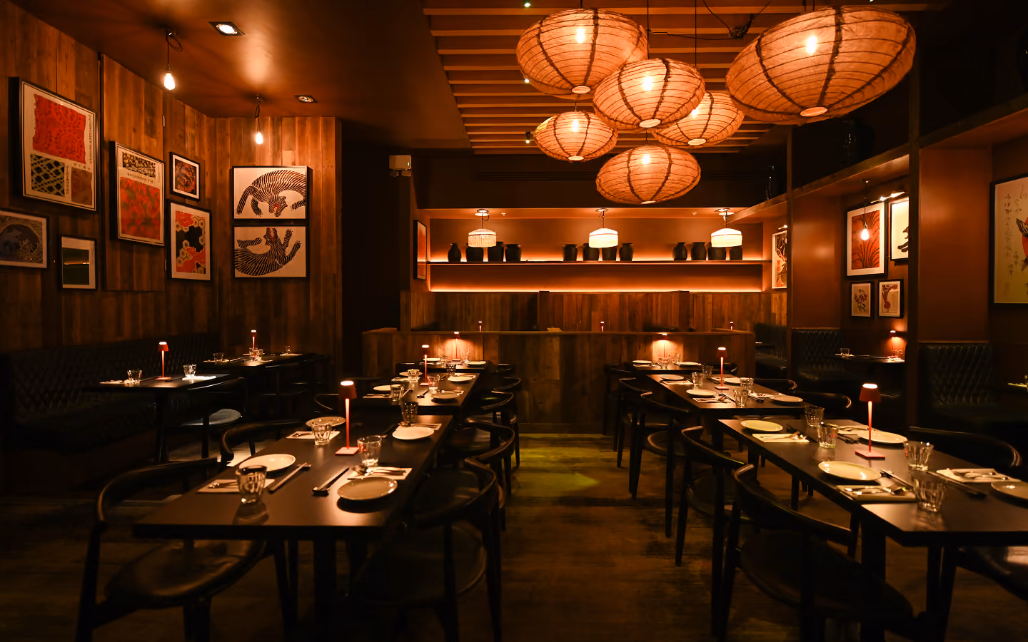 Set tables under paper lanterns in the timber-lined dining room at Kaldero