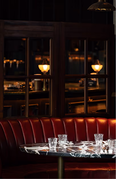 Red leather banquette and marble table set with glassware in a private dining room