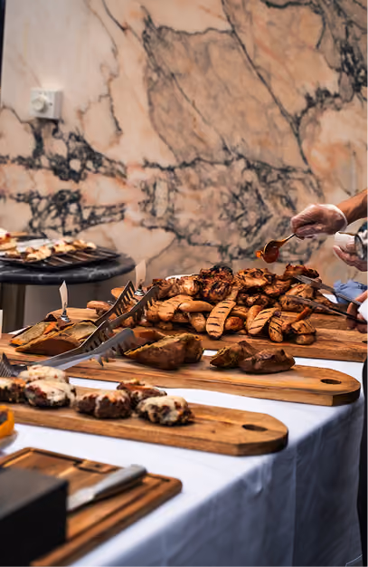 Grilled sausages, skewers and baked potatoes served on wooden boards at a barbecue buffet
