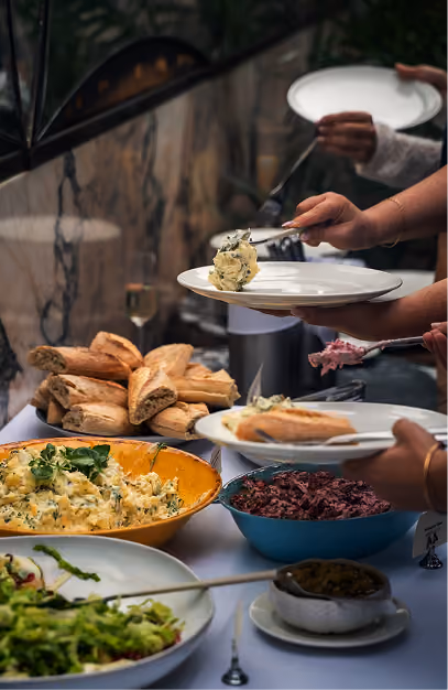 Guests serving themselves from a buffet of breads, salads and sharing dishes