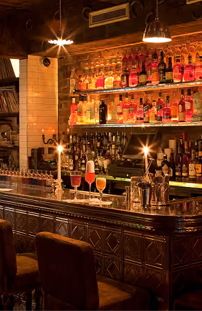 Vintage Cocktail Club's ornate bar shelving stocked with bottles, lit by warm ambient lighting