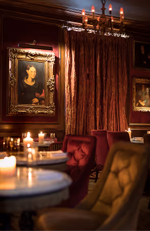 Peruke & Periwig's candlelit dining room with red velvet booths and vintage portraits