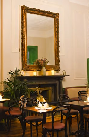 Amelia's Table dining room with ornate gold mirror and cozy fireplace seating