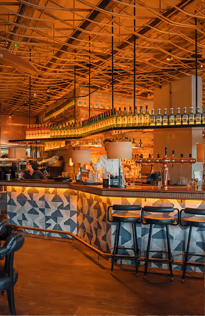 Mackenzie's curved bar counter with blue leather stools and warm lighting