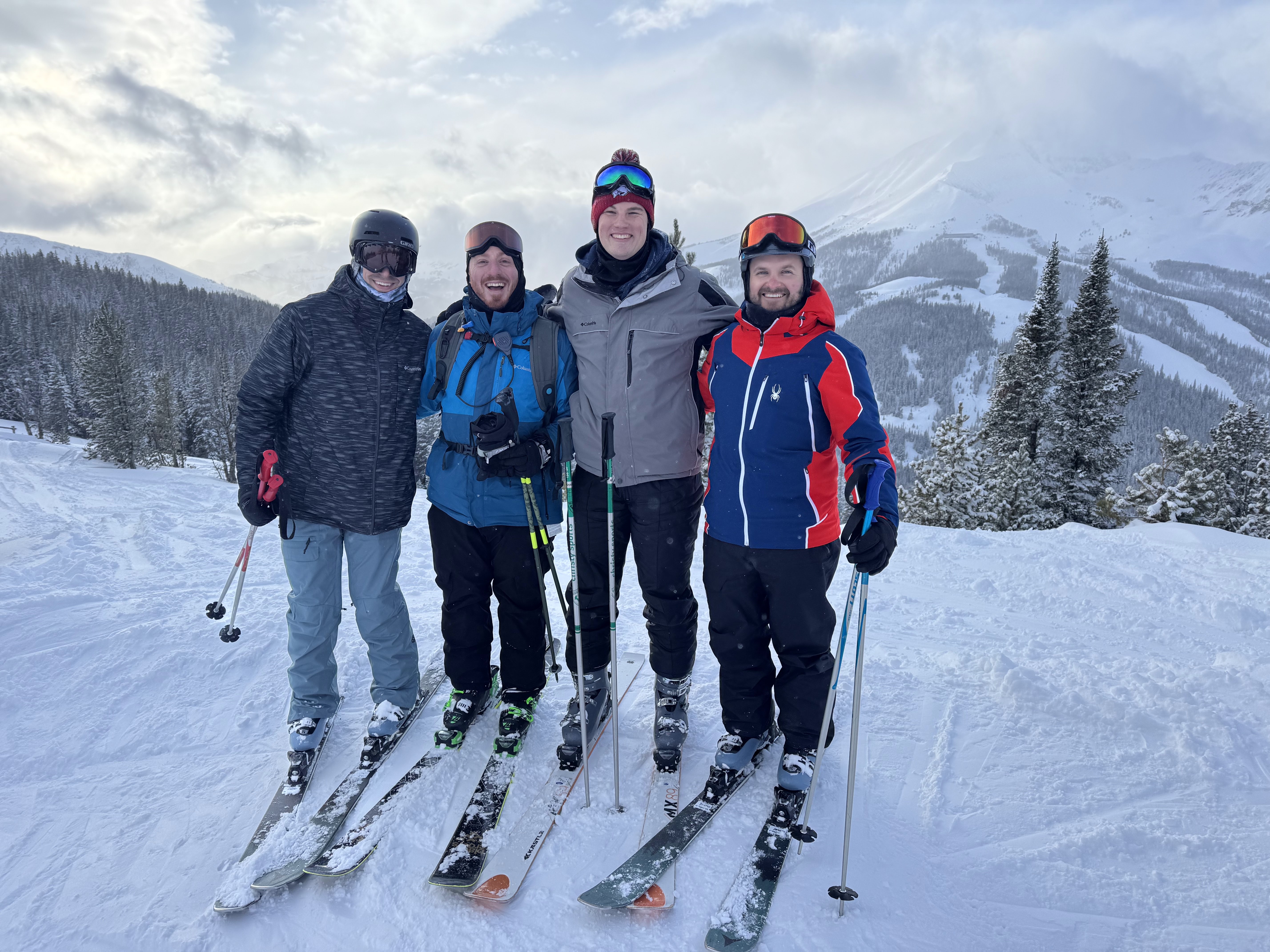 a few members of Pandowealth taking a picture on a mountain wearing skiis