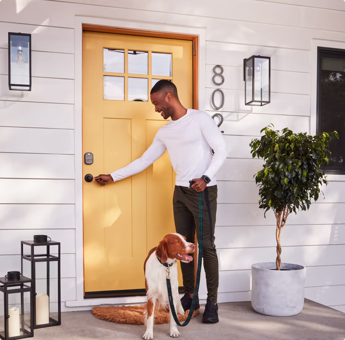 Man with his dog unlocking a smart lock on his front door.