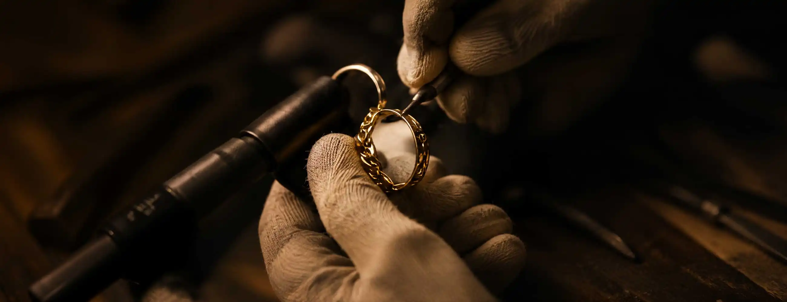 Close-up of a jeweler engraving an ornate gold ring with precision tools, warm lighting highlighting craftsmanship and fine details