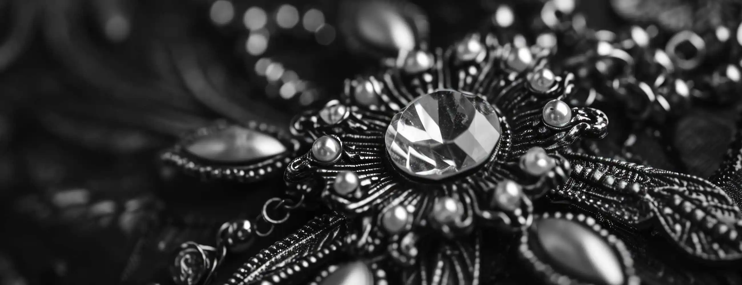 black and white macro close-up of ornate vintage jewelry with faceted gemstone centerpiece and intricate metal detailing, highlighting texture and craftsmanship