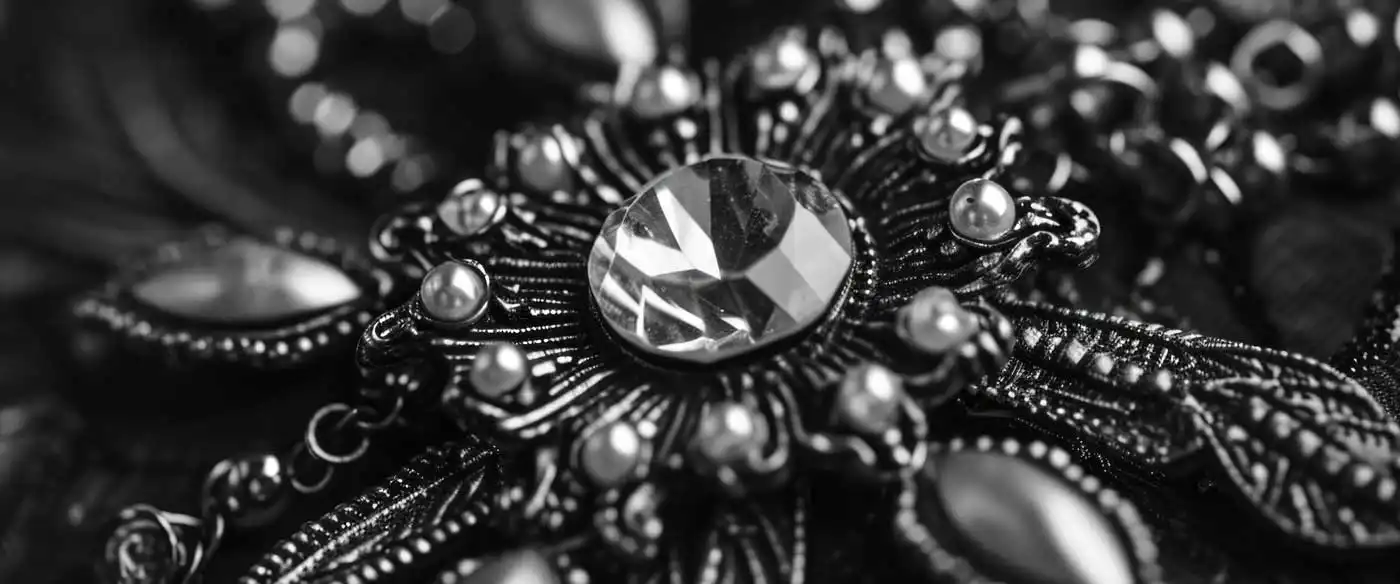 black and white macro close-up of ornate vintage jewelry with faceted gemstone centerpiece and intricate metal detailing, highlighting texture and craftsmanship