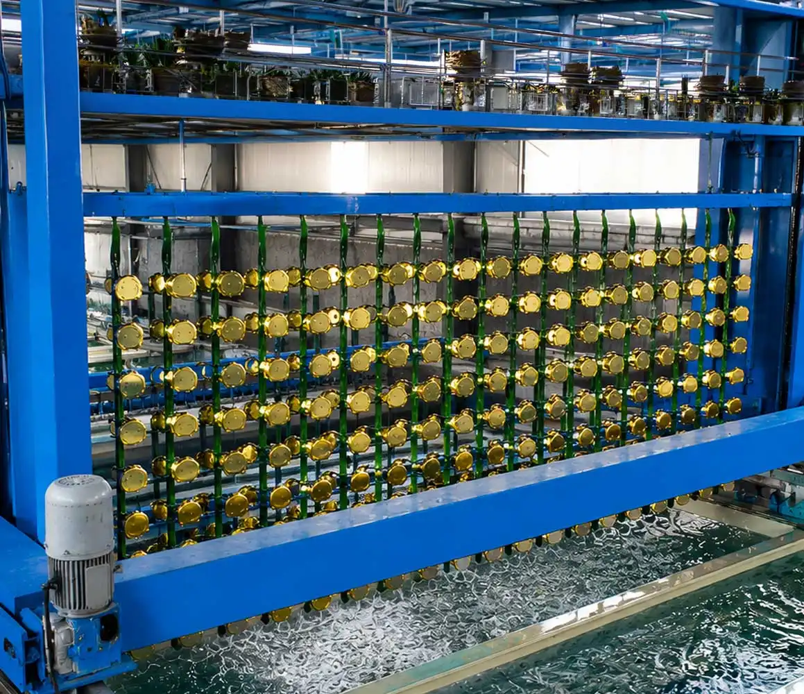 High-resolution industrial electroplating facility with blue metal gantry, black valves, and rows of gold-coated components suspended above bubbling chemical tanks in a modern factory setting.