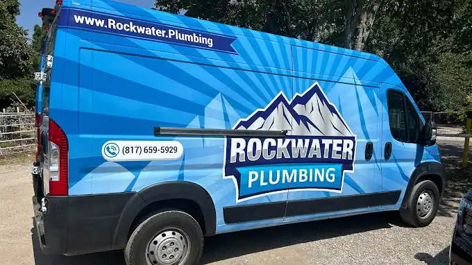 Blue Rockwater Plumbing van with mountain logo and phone number parked on a sunny day.