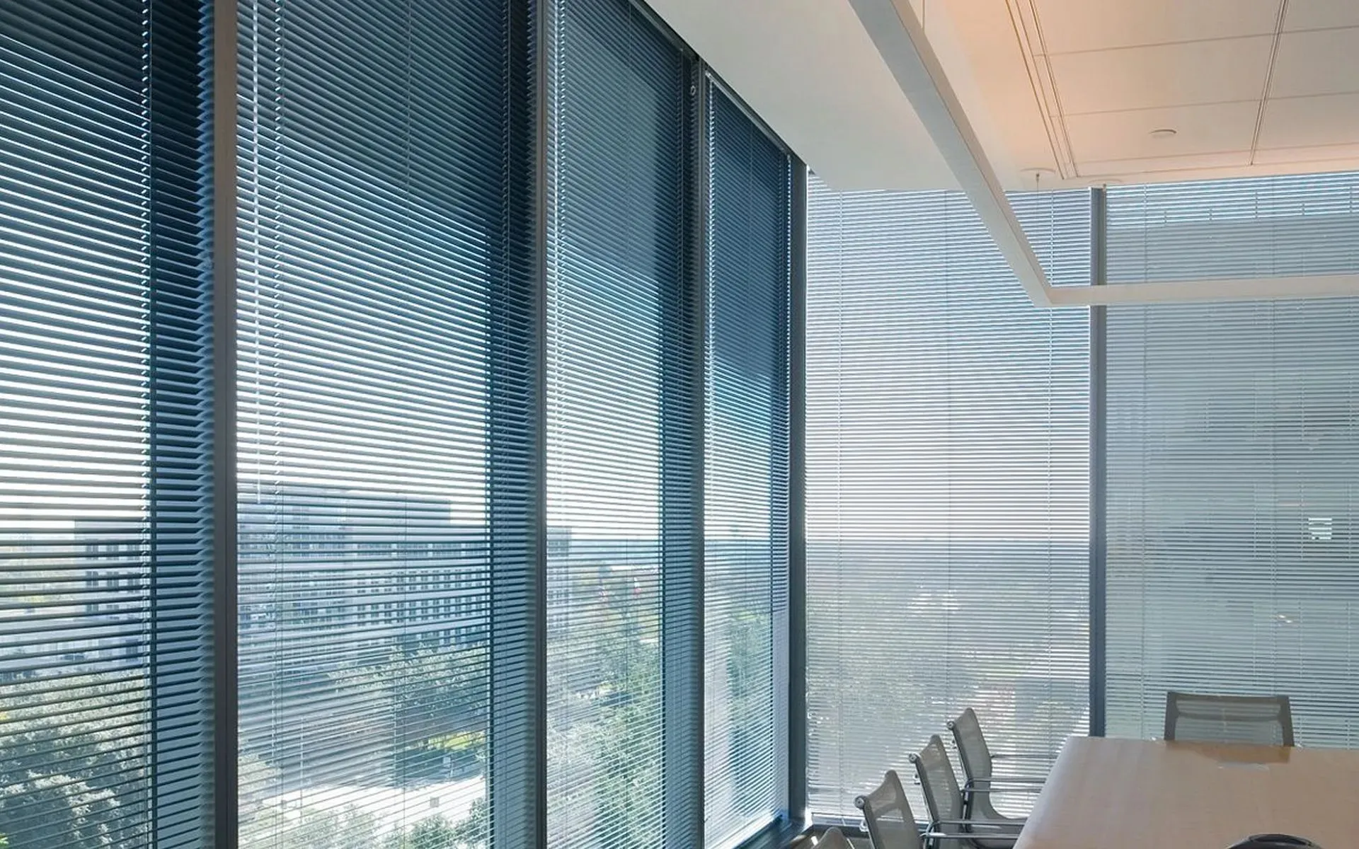 Horizontal blinds on floor-to-ceiling windows in a corporate conference room
