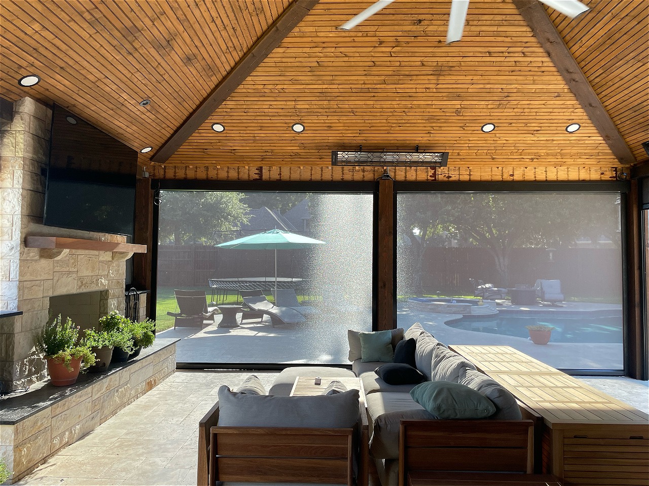 Covered patio with exterior solar screens lowered, overlooking a backyard pool