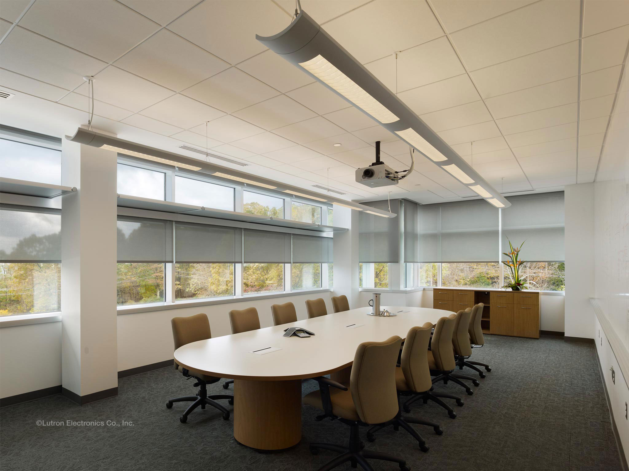 Conference room with gray solar roller shades partly lowered over the windows