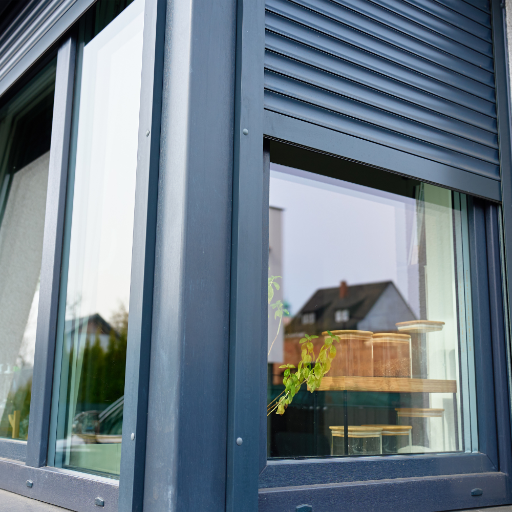 Dark gray exterior rolling shutter partly lowered over a home window