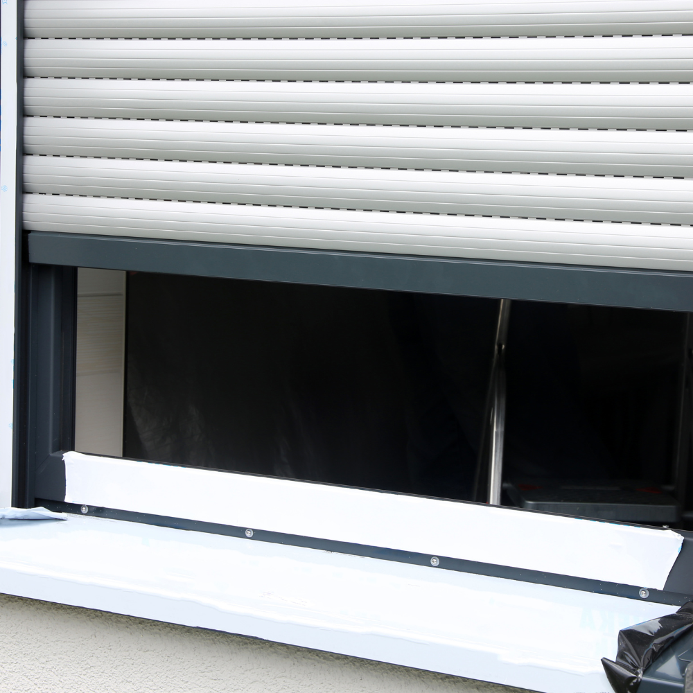 White exterior rolling shutter partly lowered over a newly installed window
