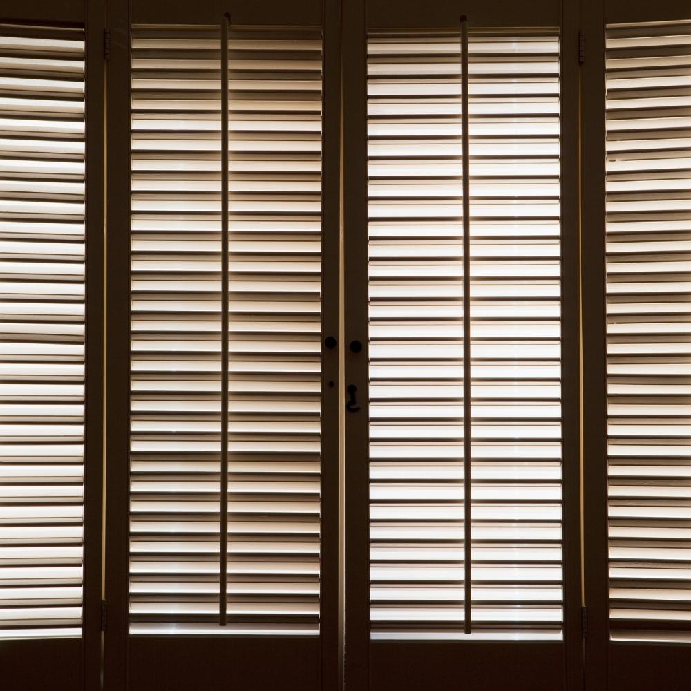 Backlit louvered shutters closed across a set of French doors