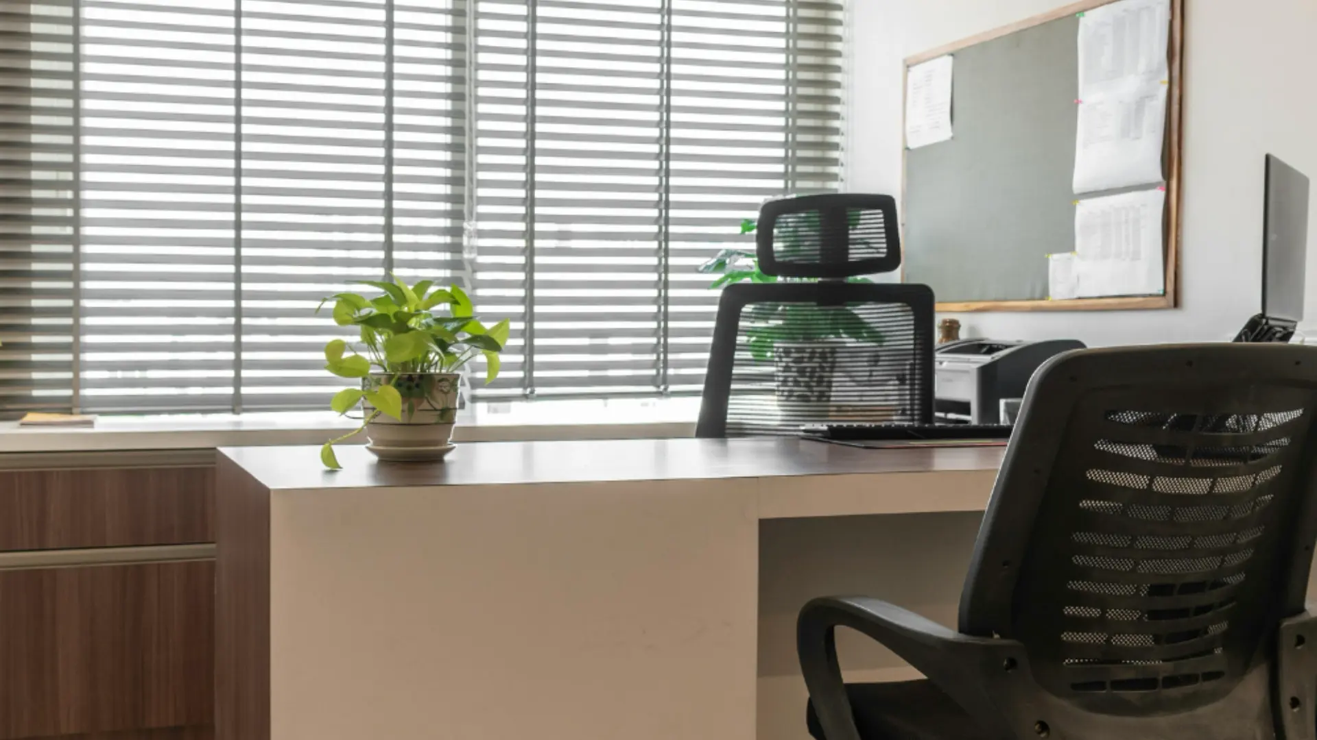 Office windows behind a desk after installing gray horizontal blinds