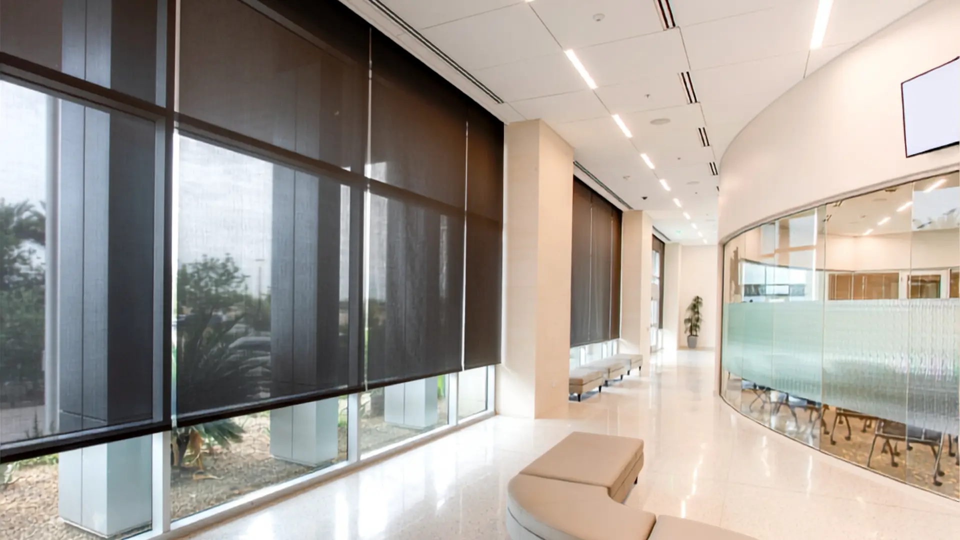 Commercial lobby windows fitted with dark solar roller shades, after installation