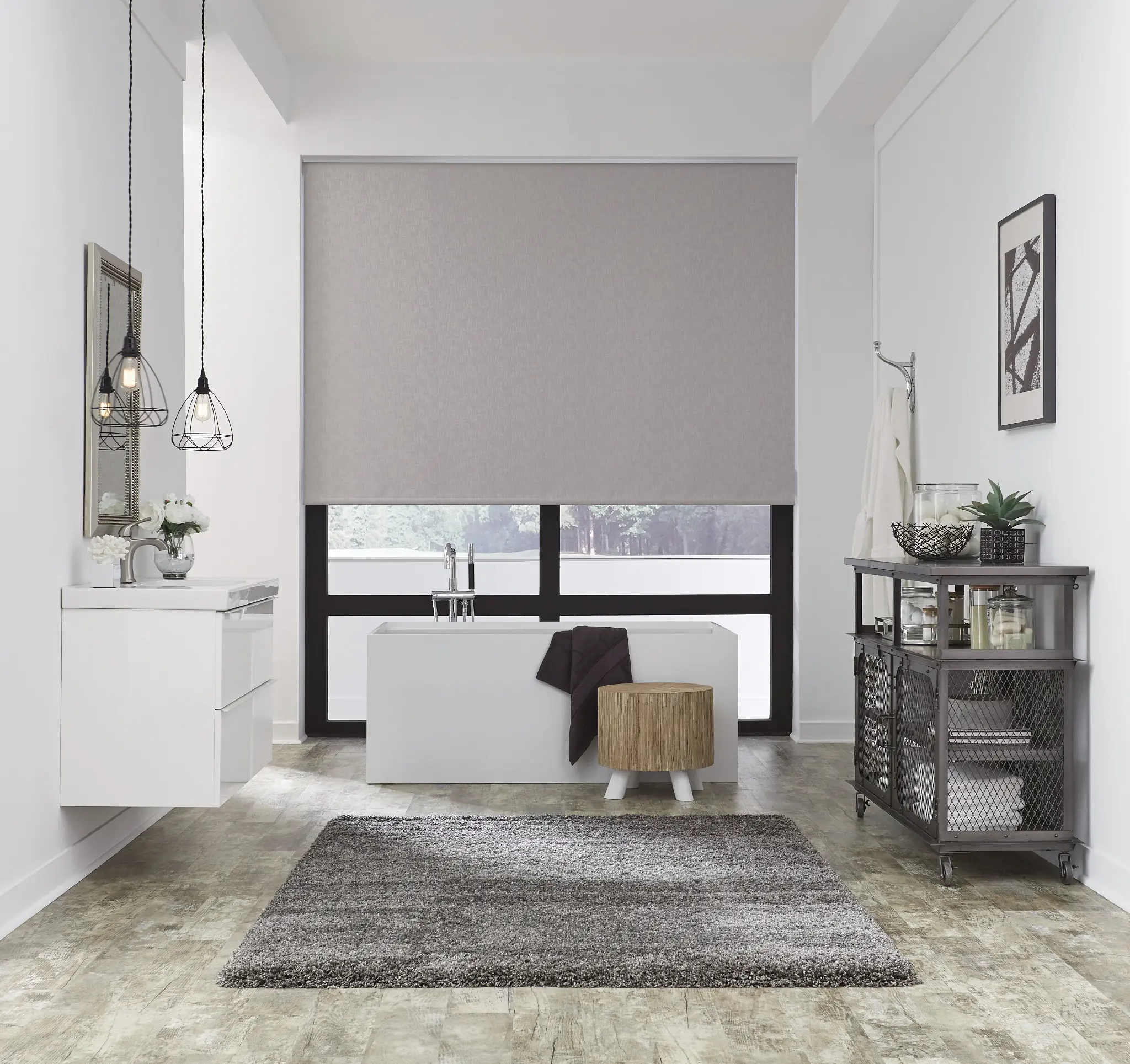 Gray roller shade partially lowered over a window behind a freestanding bathtub