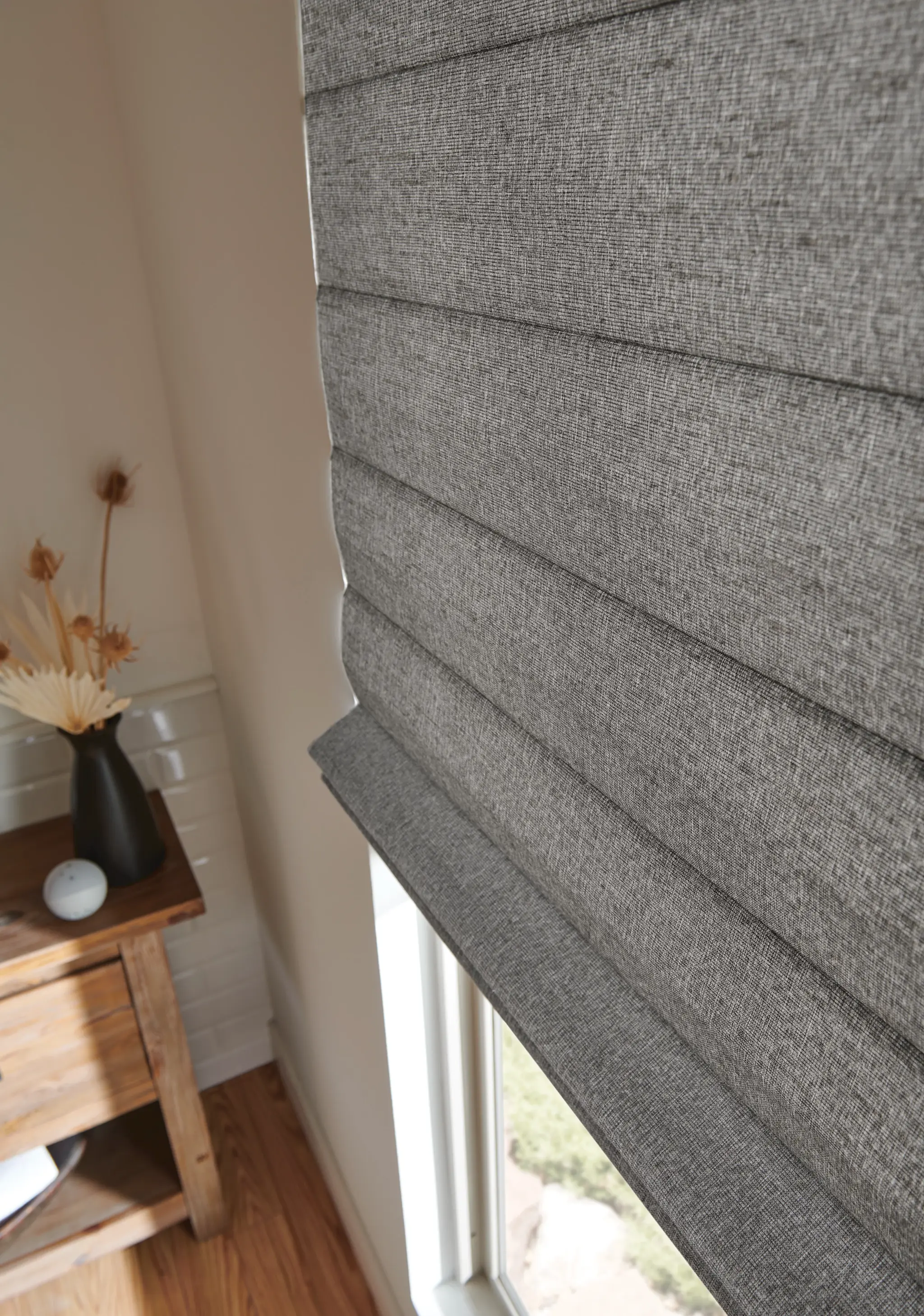 Close-up of a charcoal linen-look classic Roman shade on a window