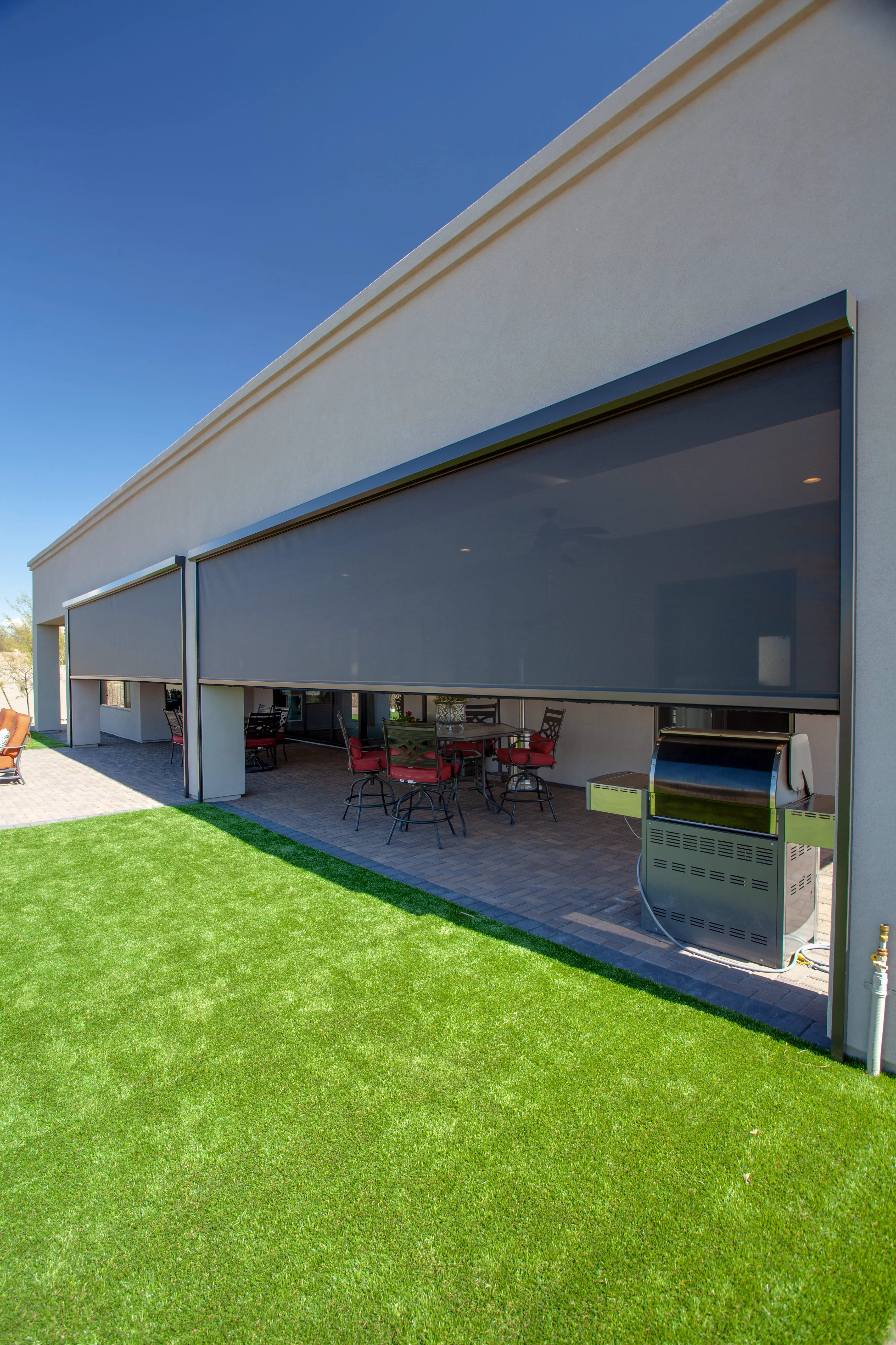 Exterior solar screens partially lowered across a large covered patio