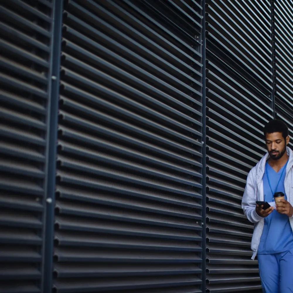 Healthcare worker walking past dark metal security shutters on a building