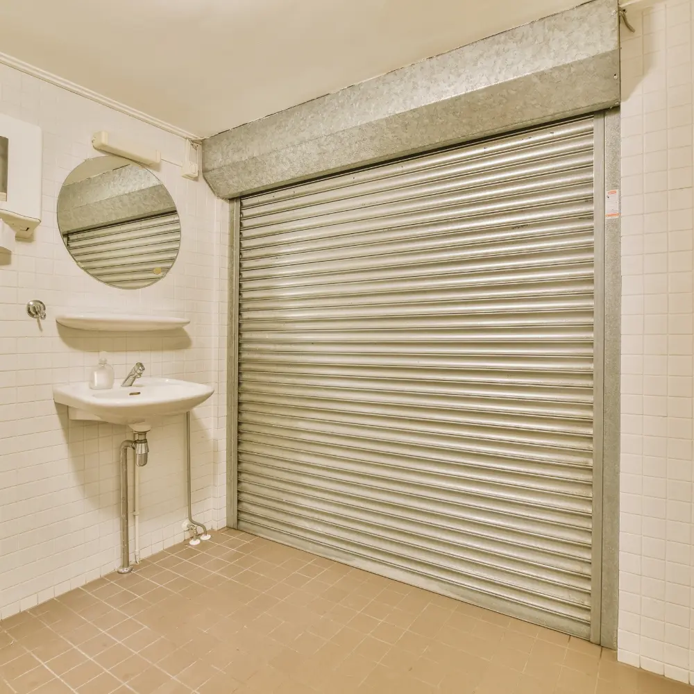 Closed roll-down metal security shutter inside a tiled room