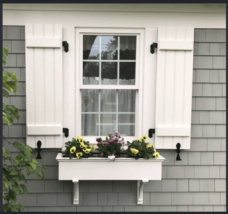 White board and batten exterior shutters on a shingled home with a flower box