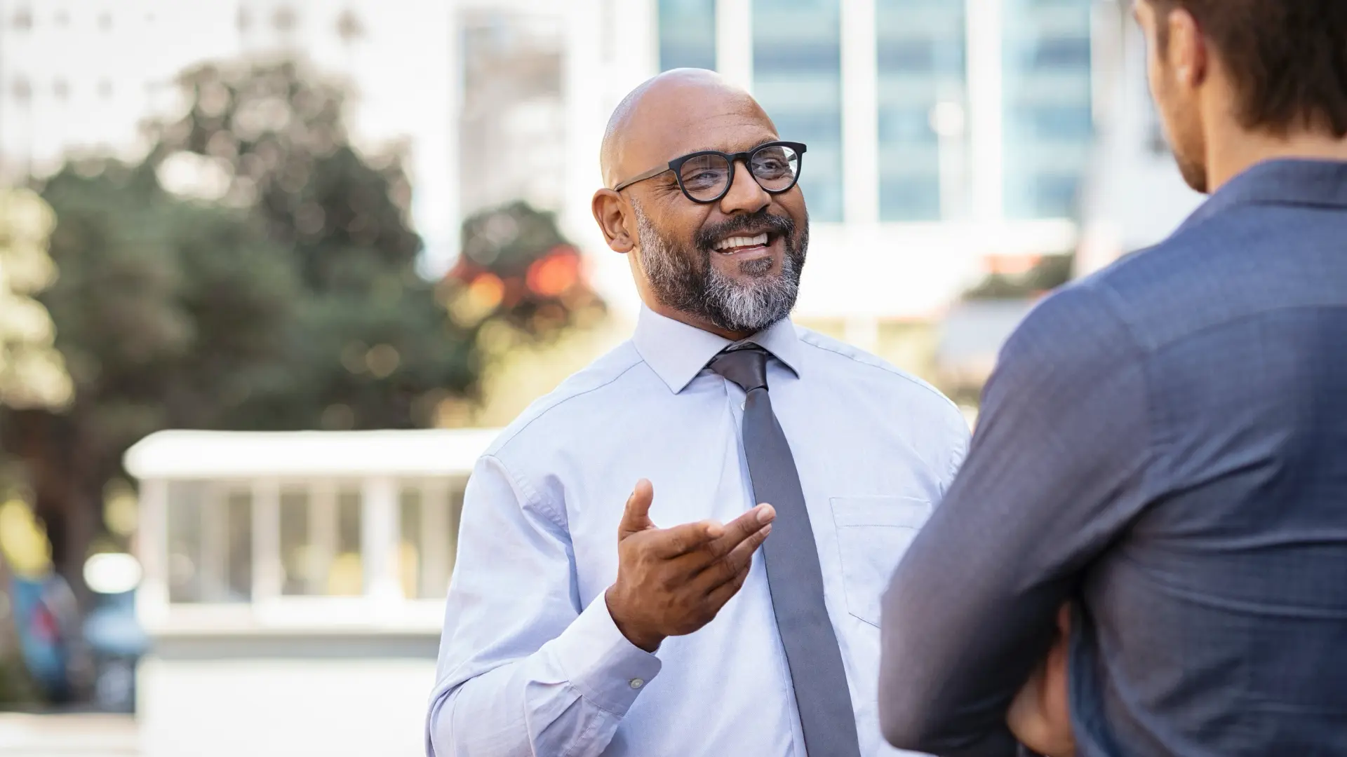 Smiling consultant in a shirt and tie talking with a client outdoors