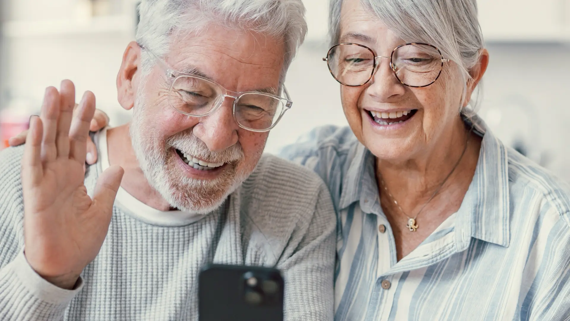 Smiling senior couple waving during a video call on a phone
