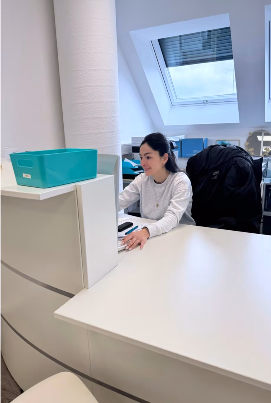 Pflegeberaterin sitzt mit Laptop an einem Schreibtisch in einem hellen Büro